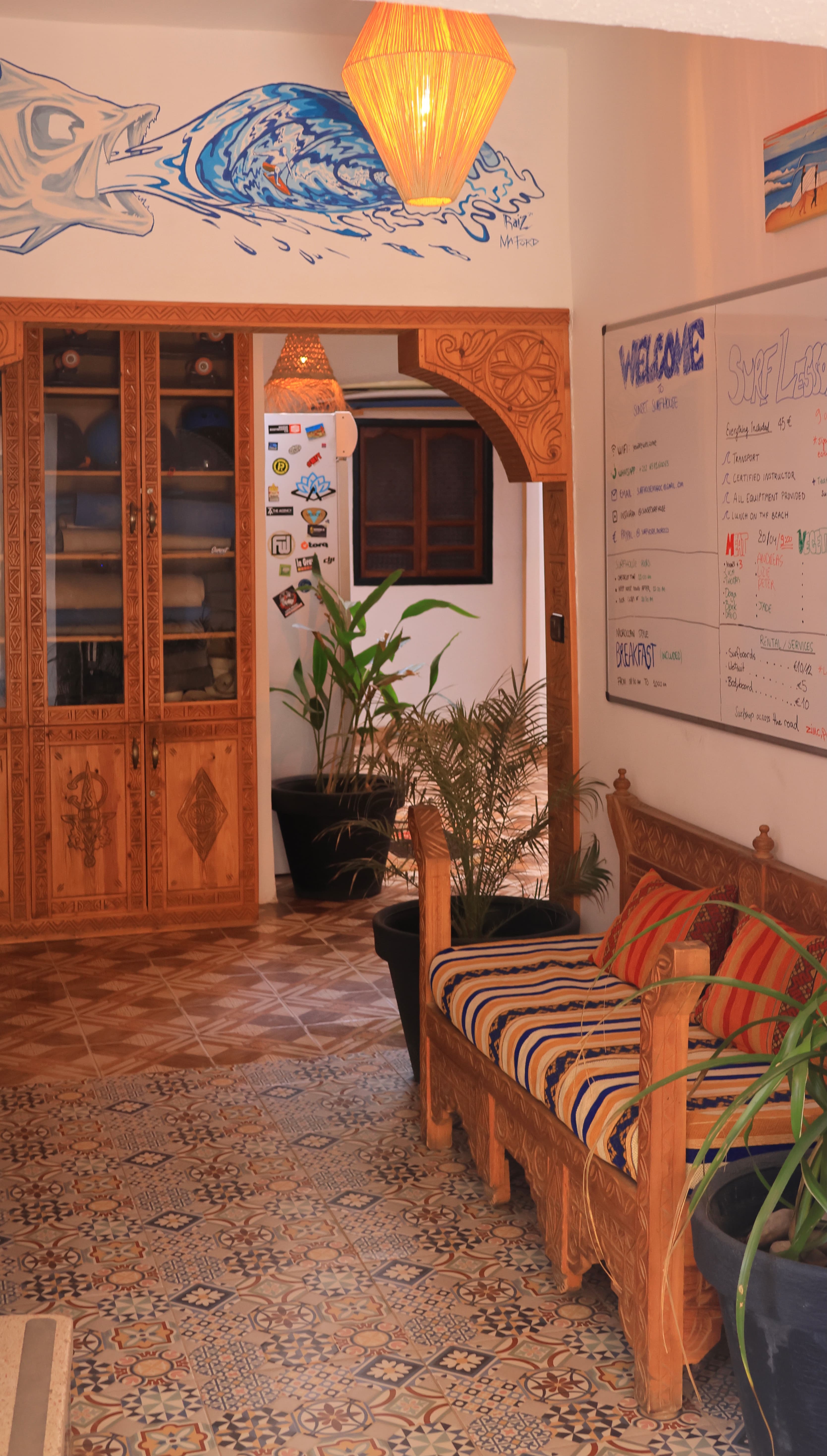 Guests sitting and talking on soft-top surfboards on the beach beside Sunset Surf House