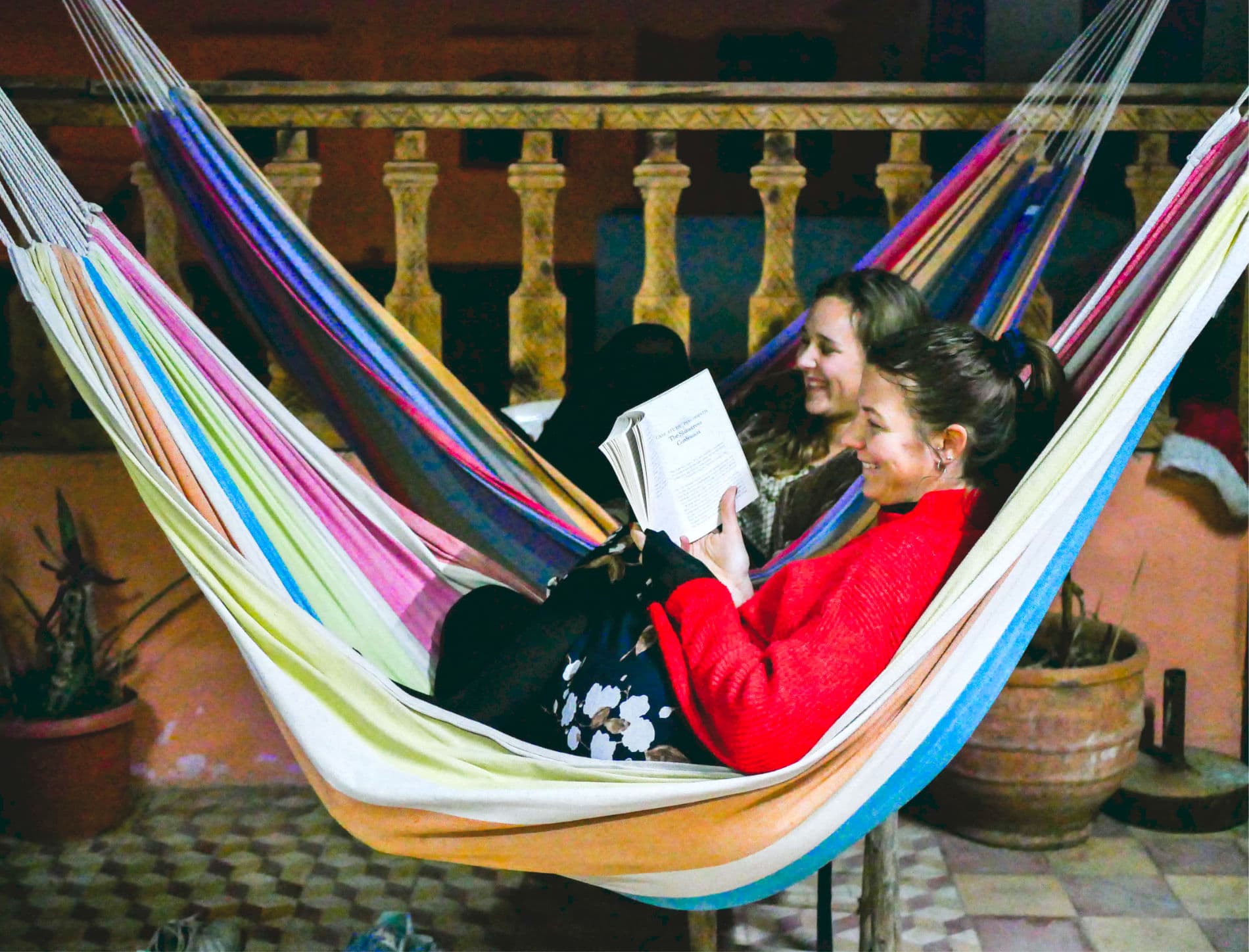 A guest resting in a striped hammock on the shaded terrace at Sunset Surf House