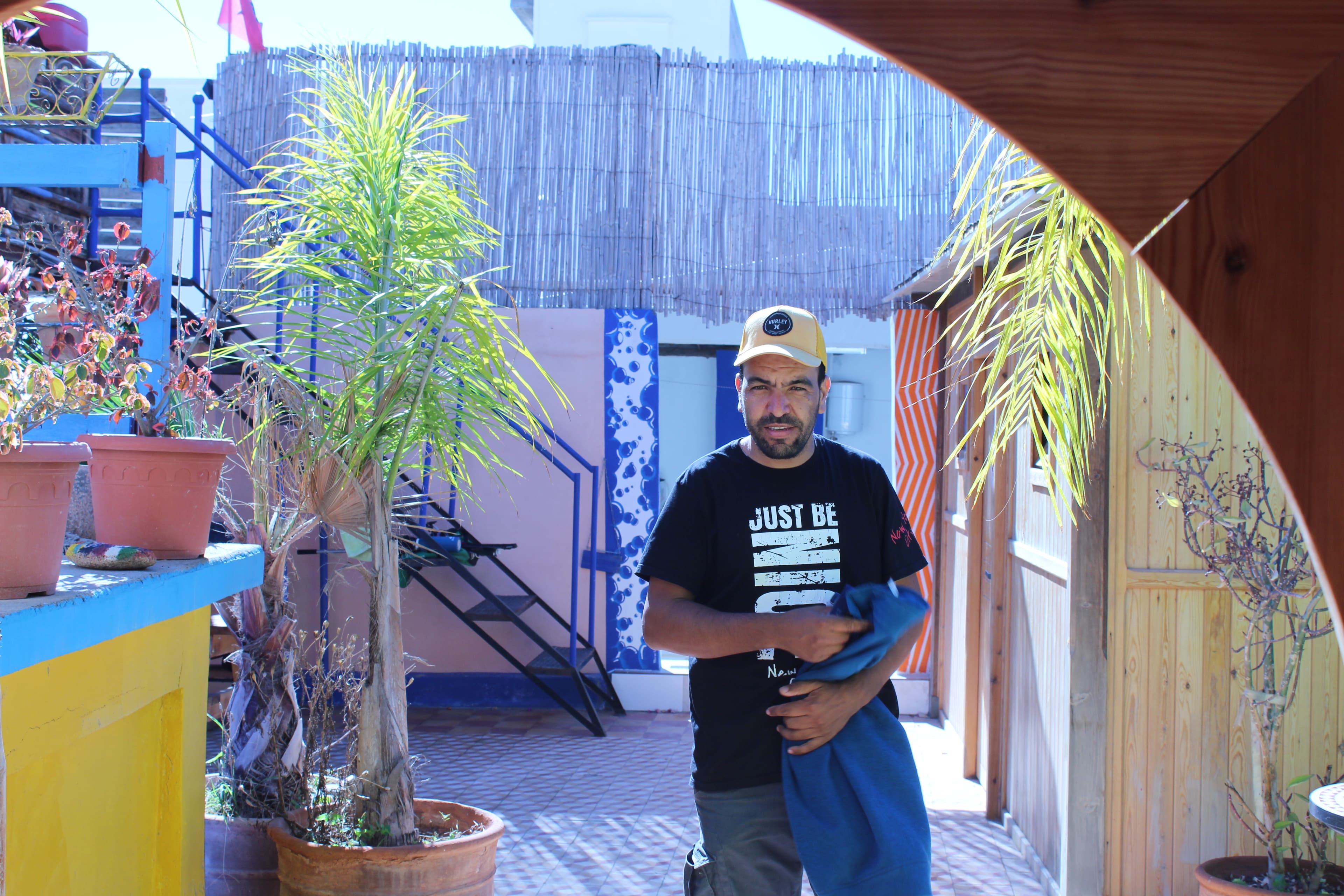 Abdoull smiling beside a blue surfboard