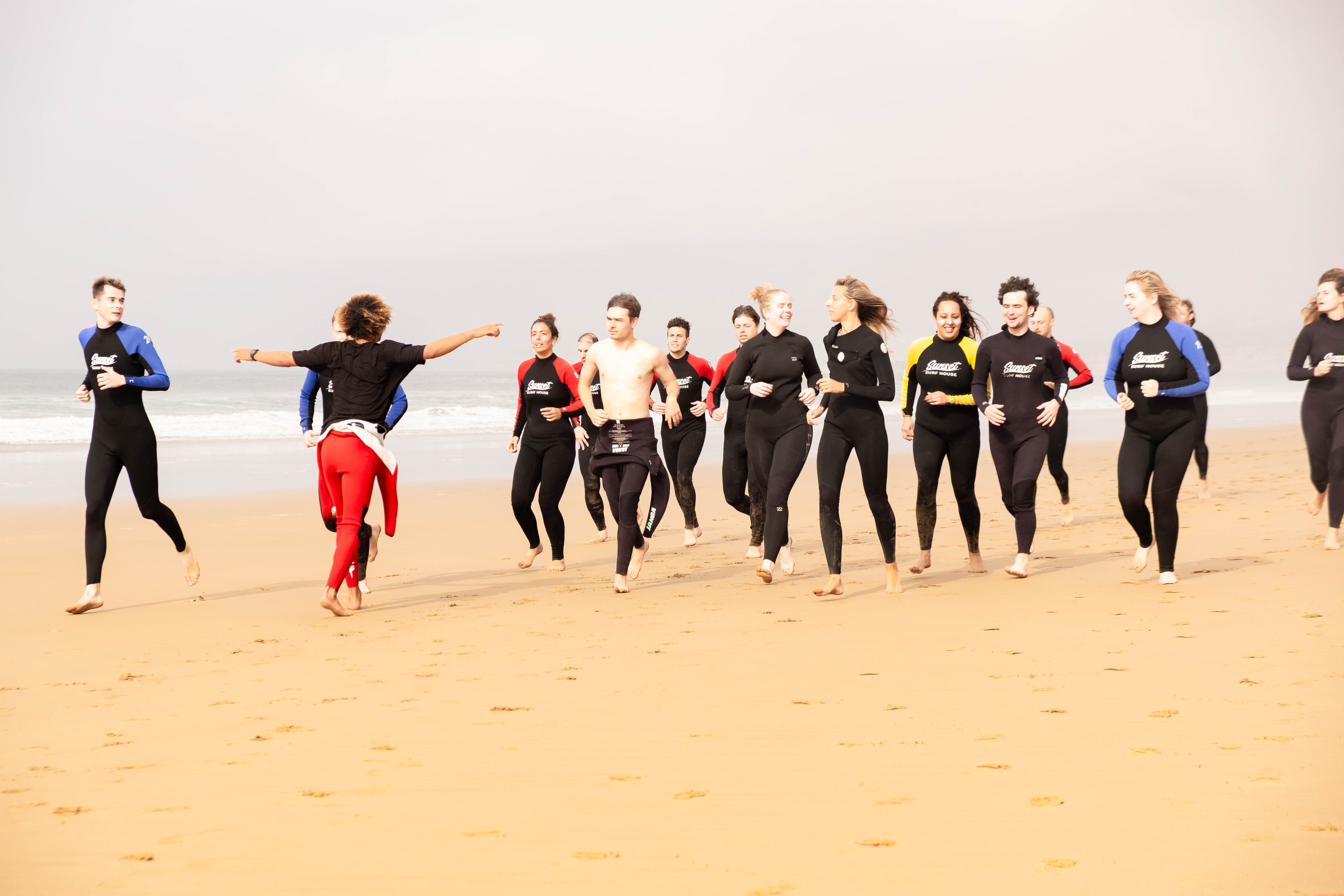 Surf students in a beach warm-up circle under a clear blue sky