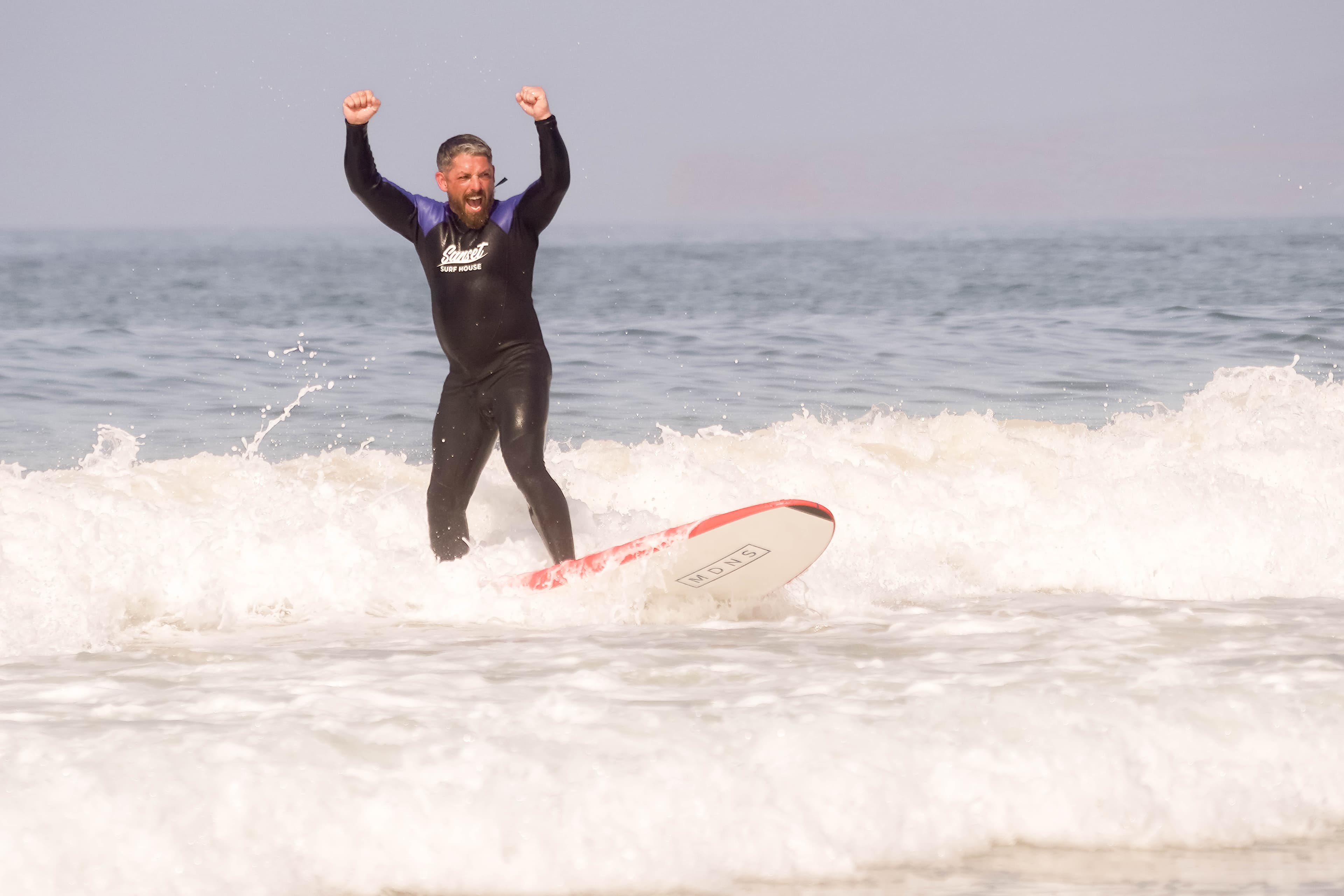 Surfers walking into manageable waves from a sandy beach