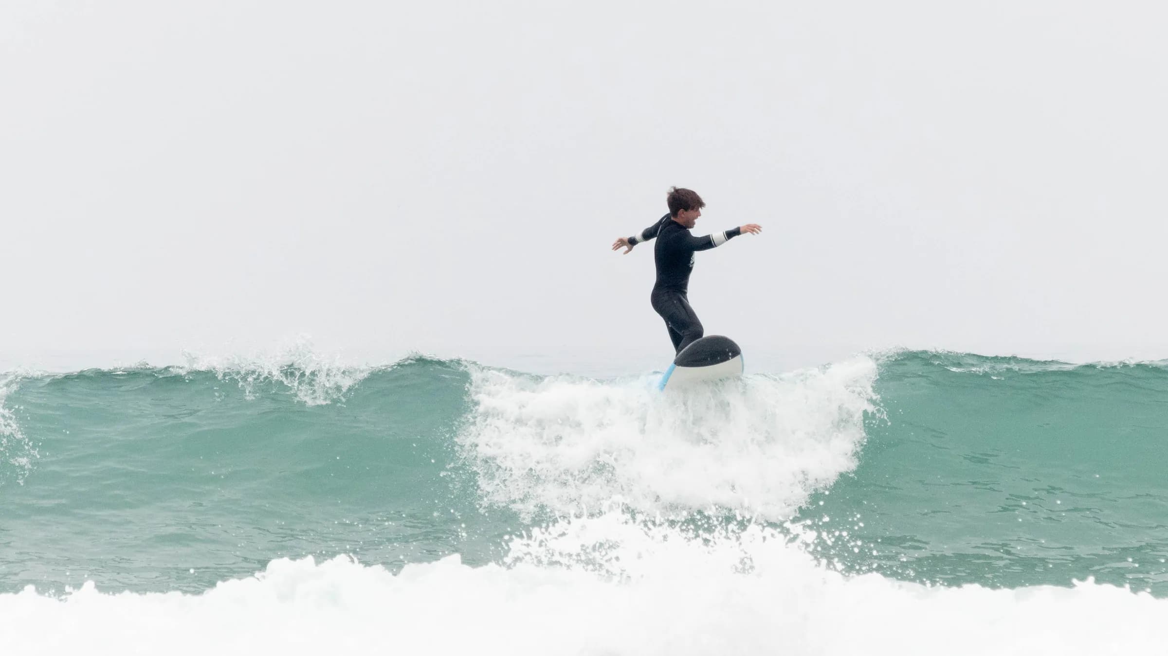 Surf students in a beach warm-up circle under a clear blue sky