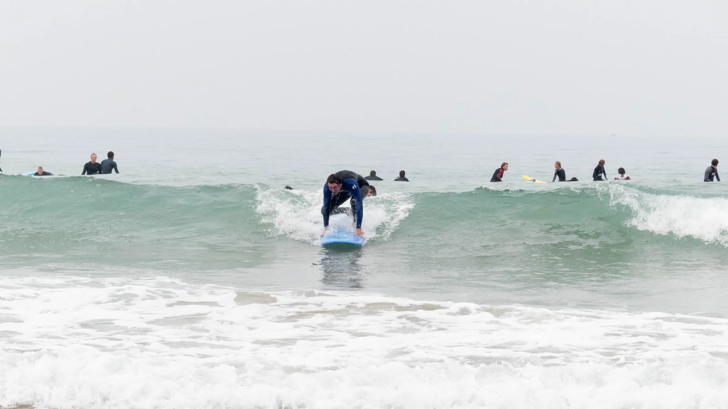 A coach running through the surf theory with the group on the sand before paddling out