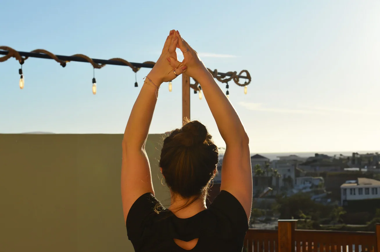 A rooftop yoga class sitting cross-legged on blue mats at Sunset Surf House