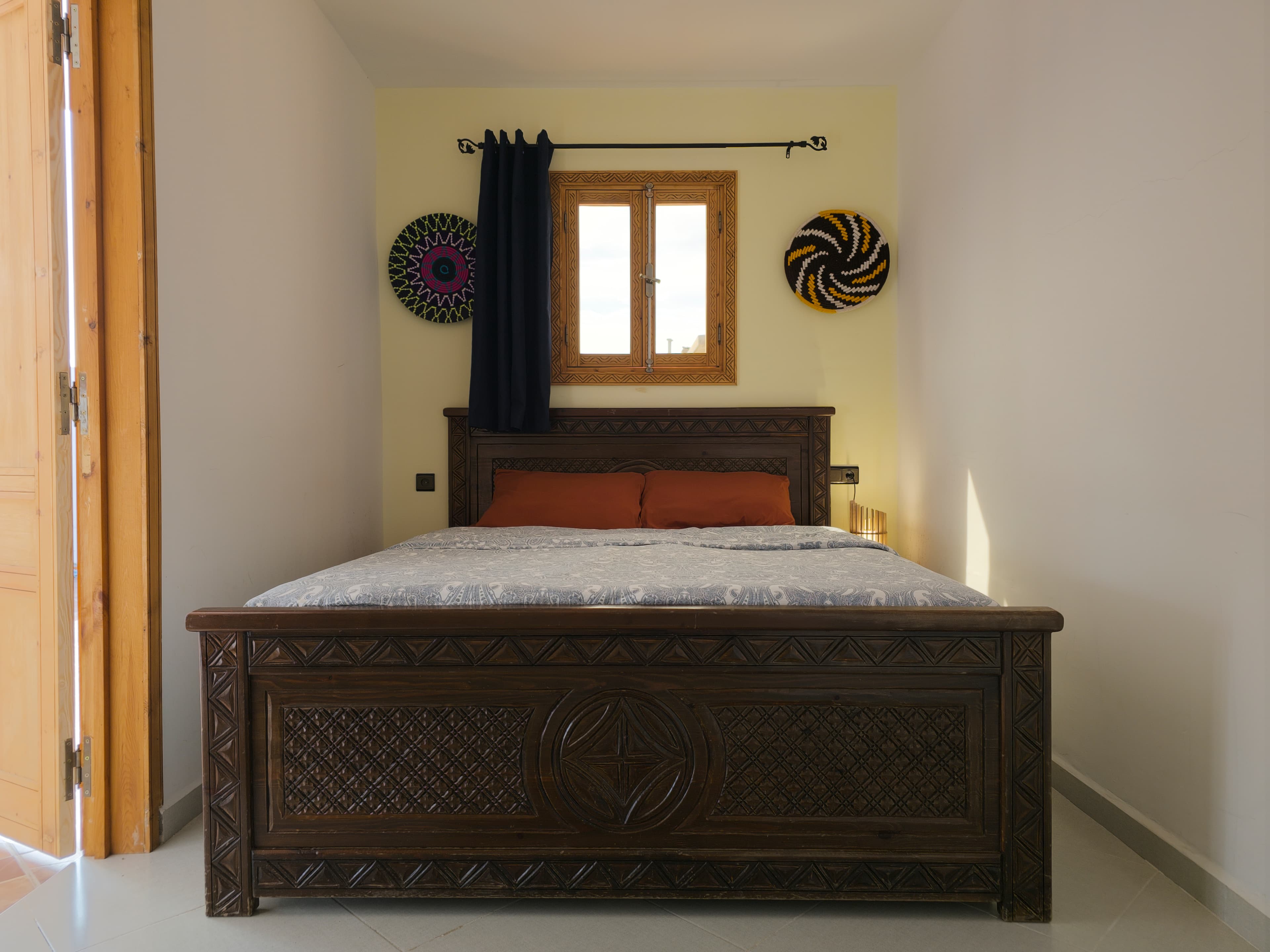 Private room at Sunset Surf House with two beds, carved wooden headboards, and Moroccan decor